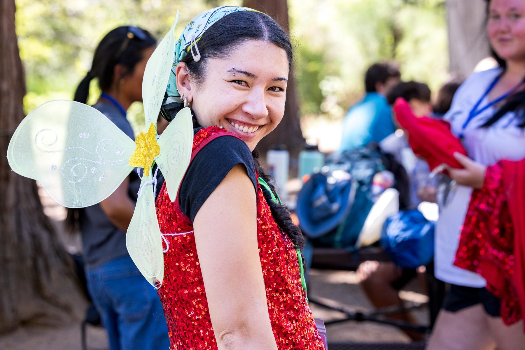 A Camp Kesem counsellor in fairy wings smiling back over her shoulder