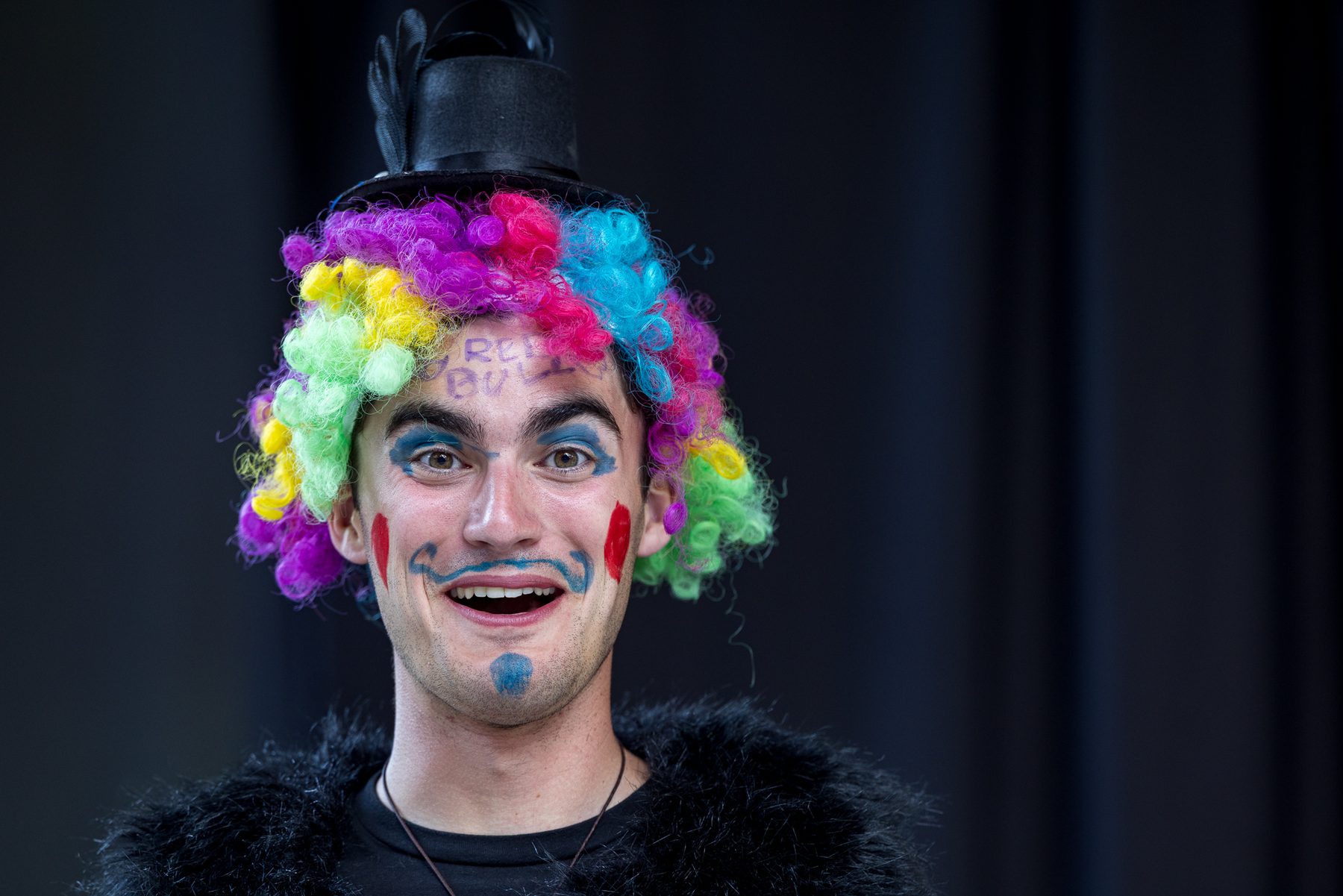 A Camp Kesem counsellor in a rainbow wig and clown face paint