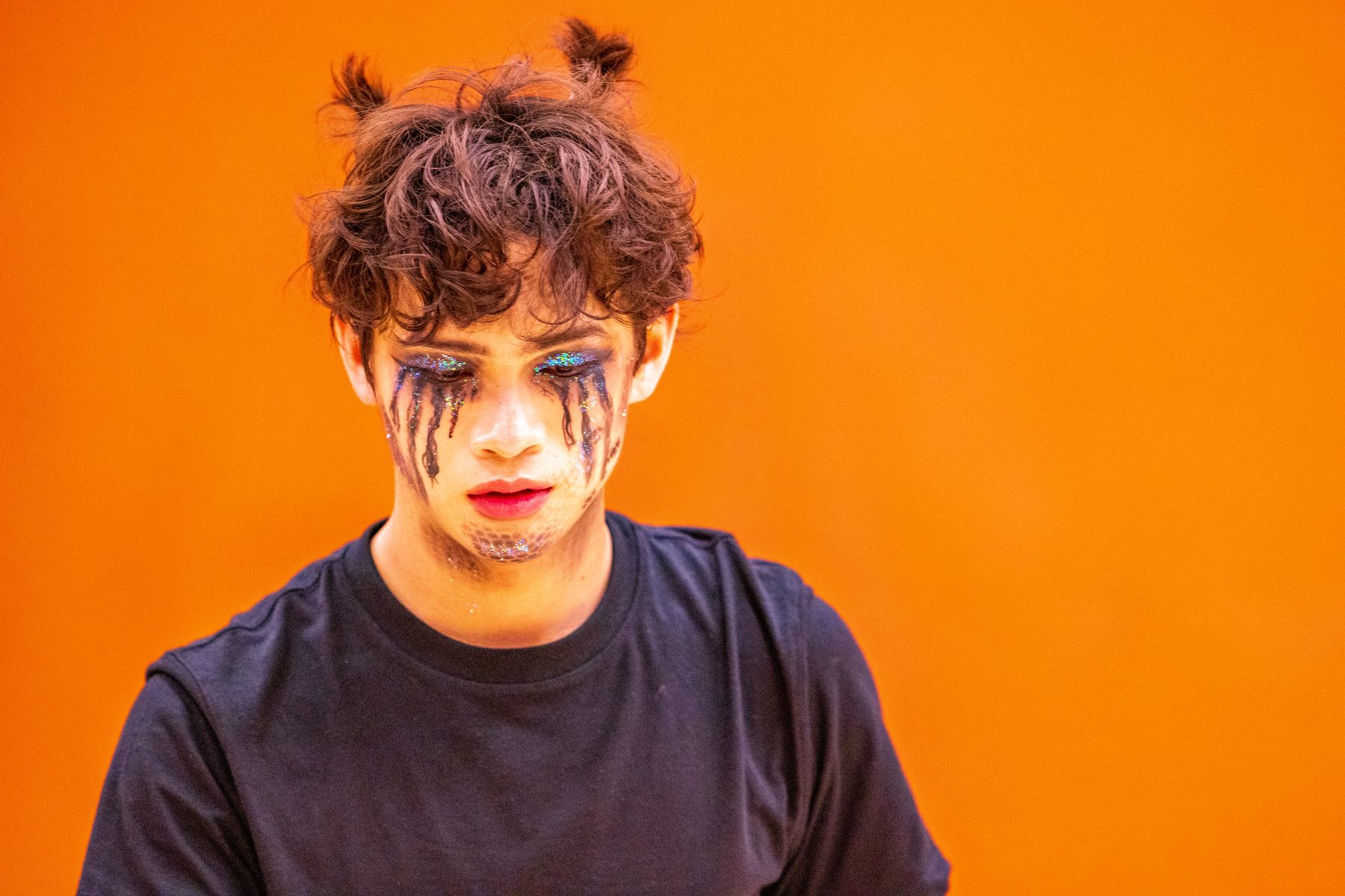 A winter percussion performer in painted tears against an orange ground